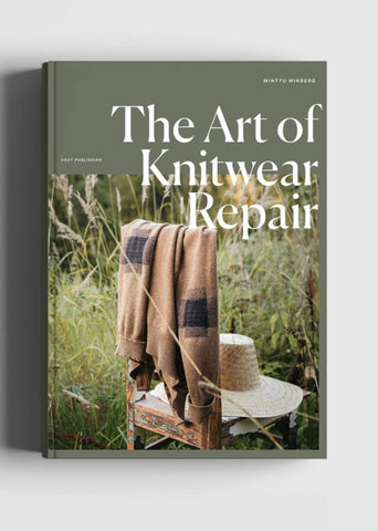 Book titled 'The Art of Knitwear Repair' with a cover featuring a blanket draped over a  chair in a natural outdoor setting.